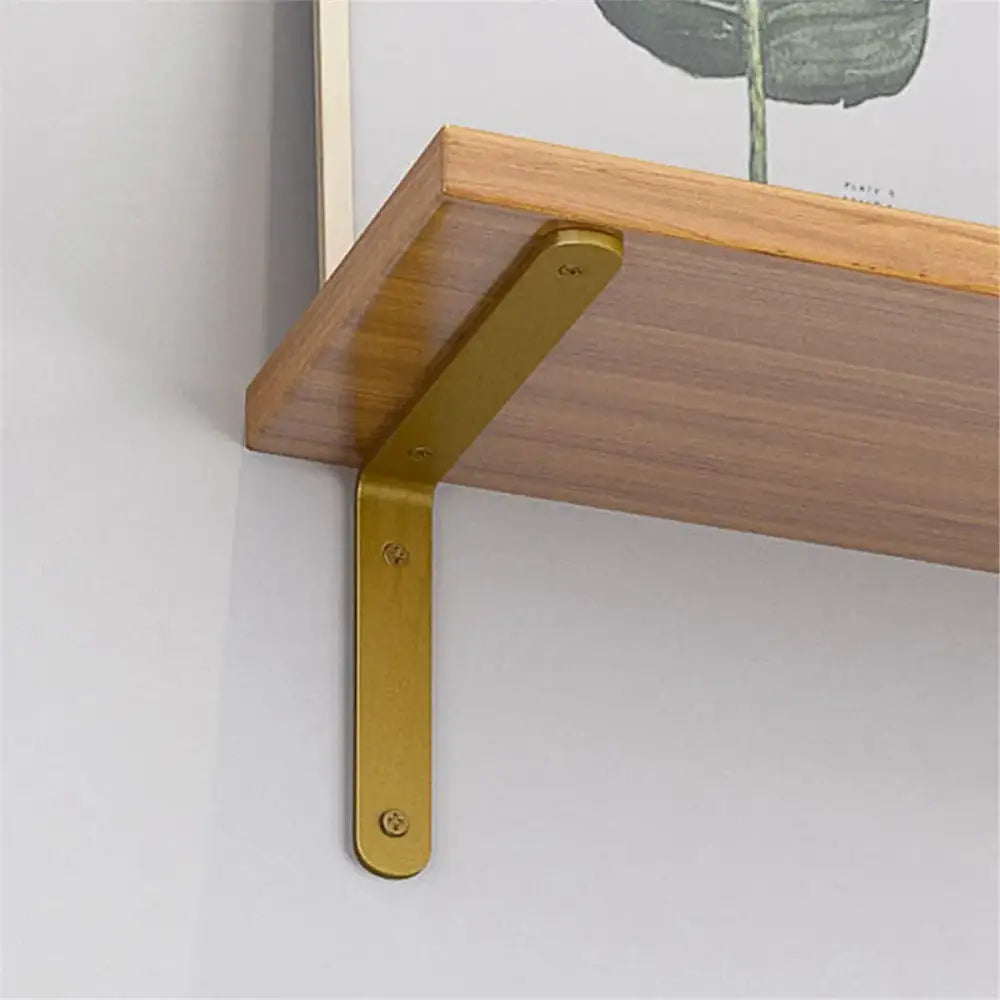 Gold L-shaped wall shelf bracket with screw holes, holding a wood shelf