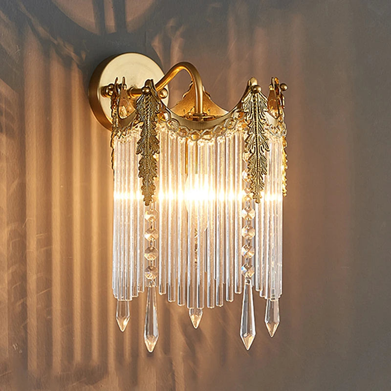 Gold crystal wall sconce with arched frame and dangling crystal strands, lit