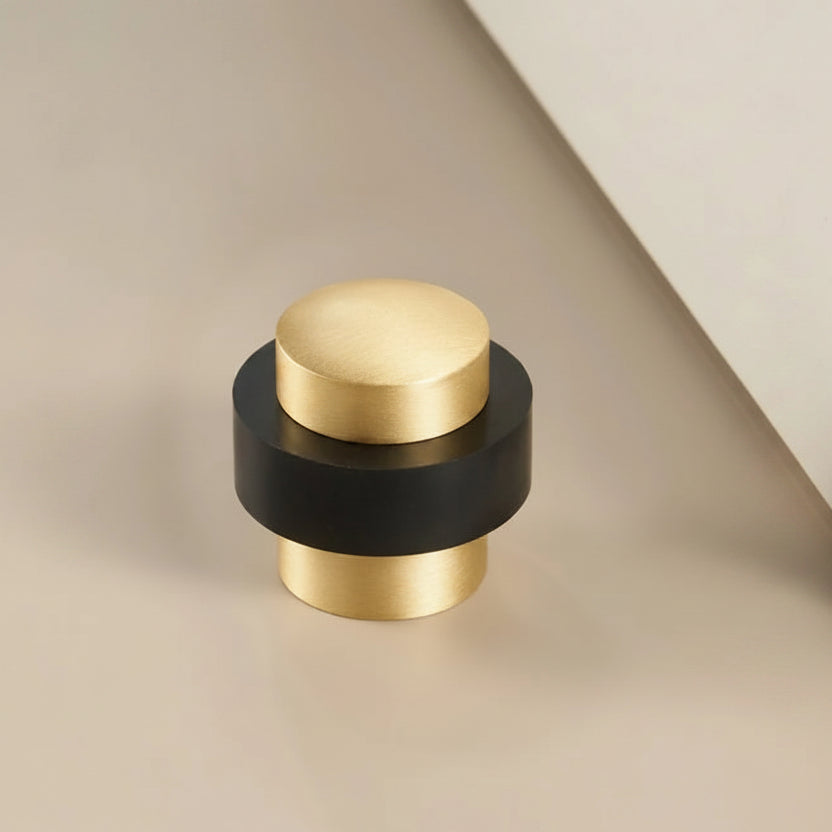 Round floor bumper door stop with gold cap and black base, low-profile