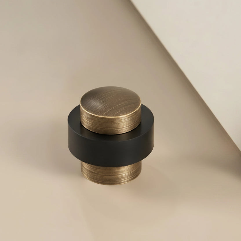 Round brass door stop with antique bronze top and black base, floor bumper