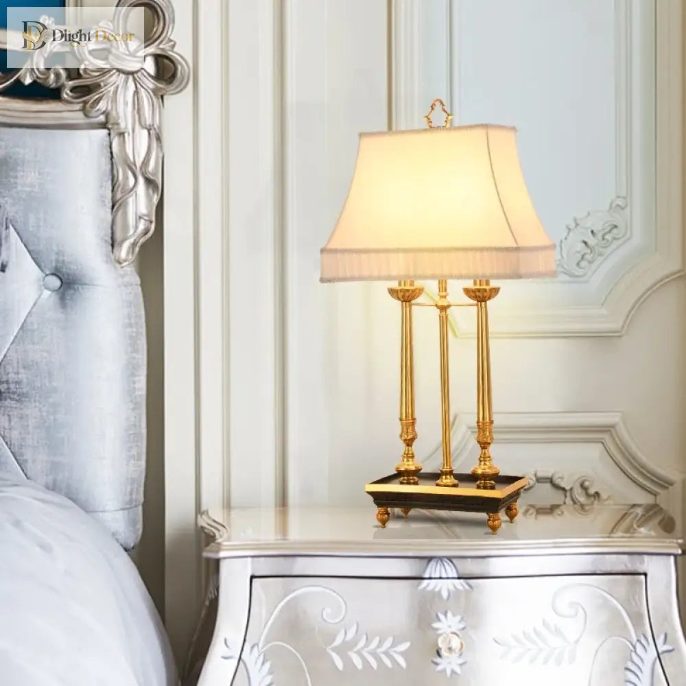 Brass LED desk lamp with beige fabric shade on a carved white console