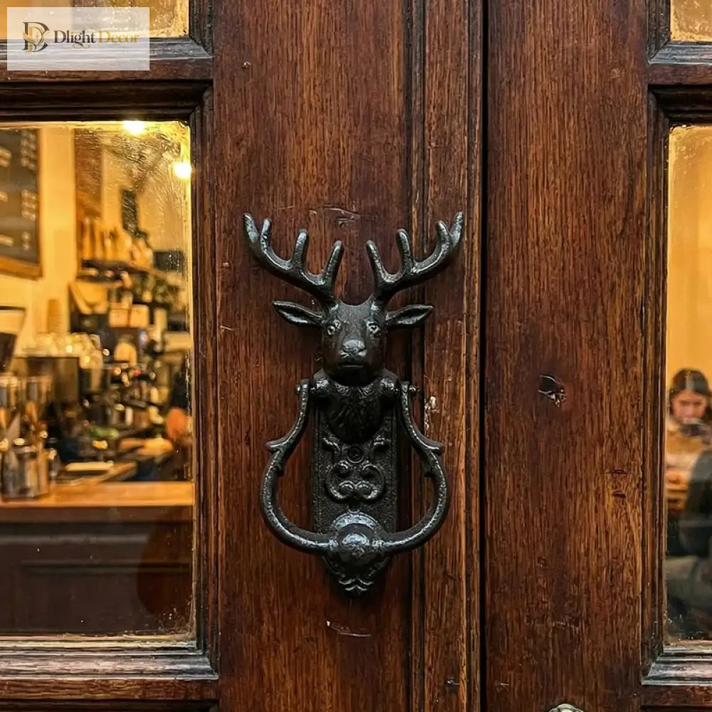Cast iron deer head door knocker attached to a wooden door panel