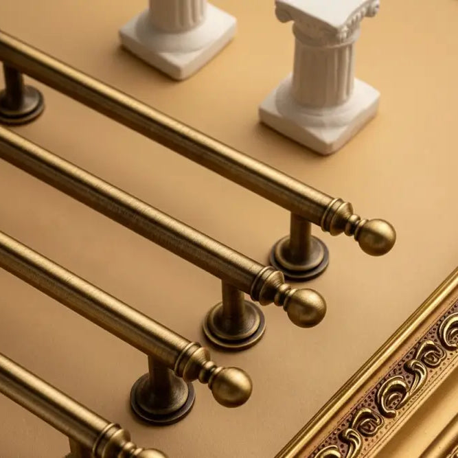 Set of brushed brass T-bar cabinet pulls with ball finial ends and curved base plates