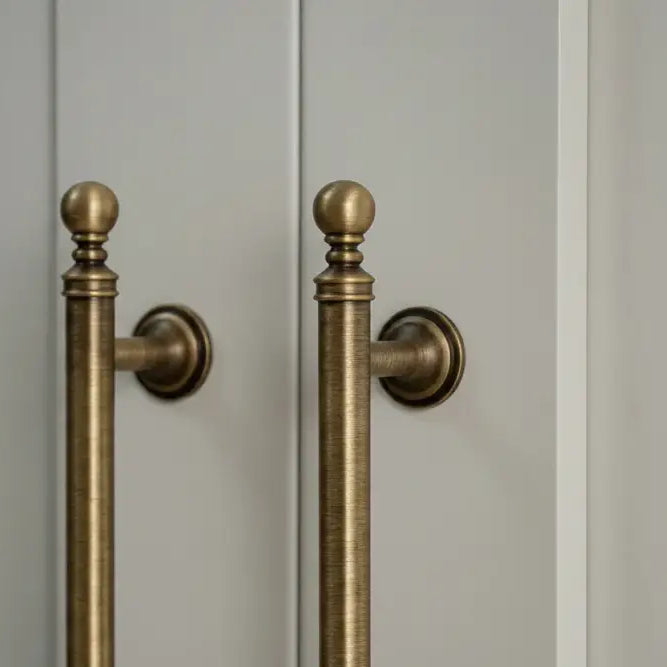 Brushed brass T-bar cabinet pull with round backplate and finial ends, wall mount