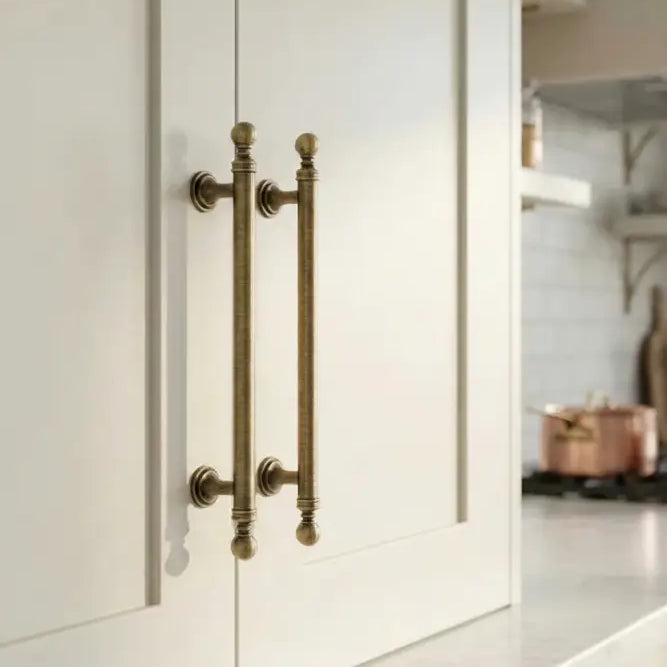 Brushed brass double T-bar cabinet pull on white cabinet door, wall-mounted handles