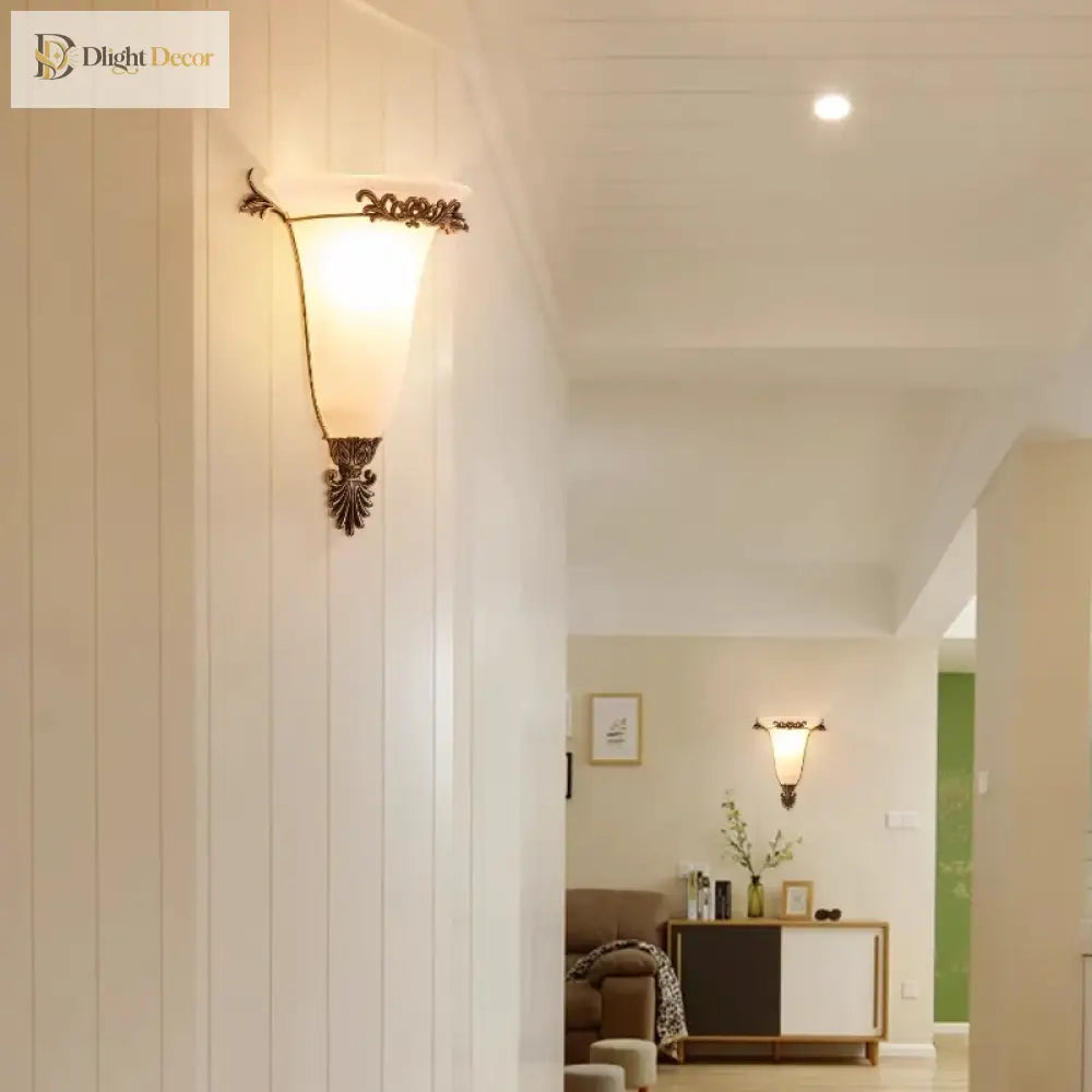 Retro gold wall sconce with frosted glass shade and detailed metal leaf ornaments