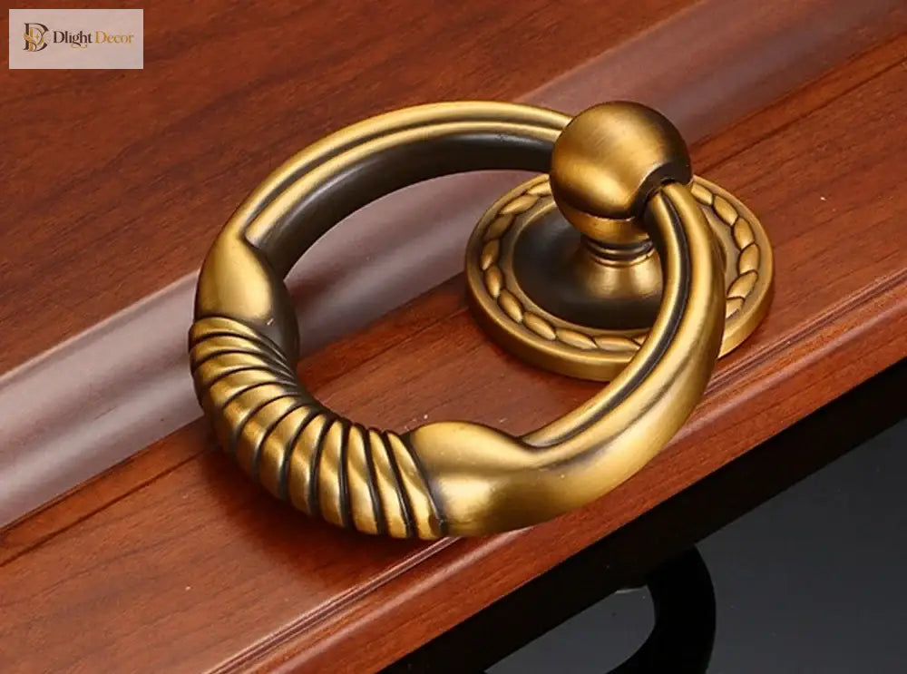 Antique brass round door knocker with coiled ring grip and circular backplate