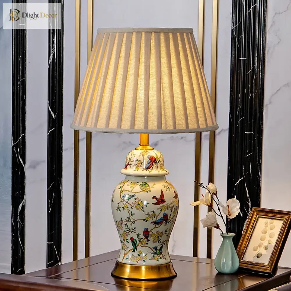 Floral ceramic lamp with pleated shade, gold pedestal base, and detailed bird motif.