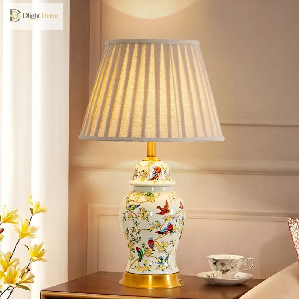 Tall ceramic table lamp, floral bird pattern on gold base, pleated fabric shade.