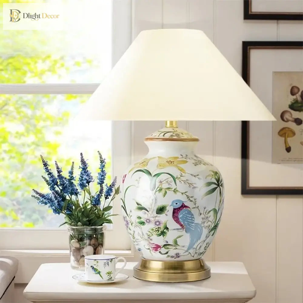 Ceramic table lamp with white shade and colorful bird-and-flower design