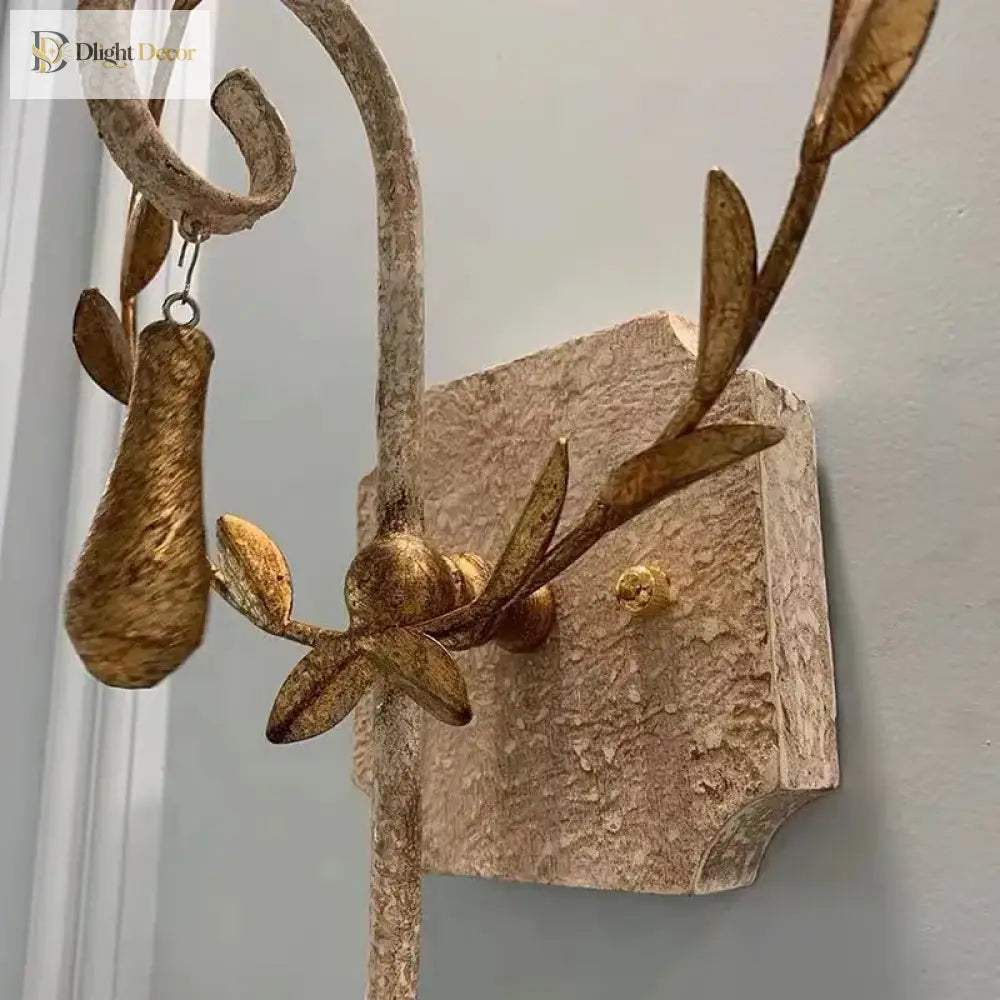 Close-up of gold leaf details and textured grey metal wall sconce backplate