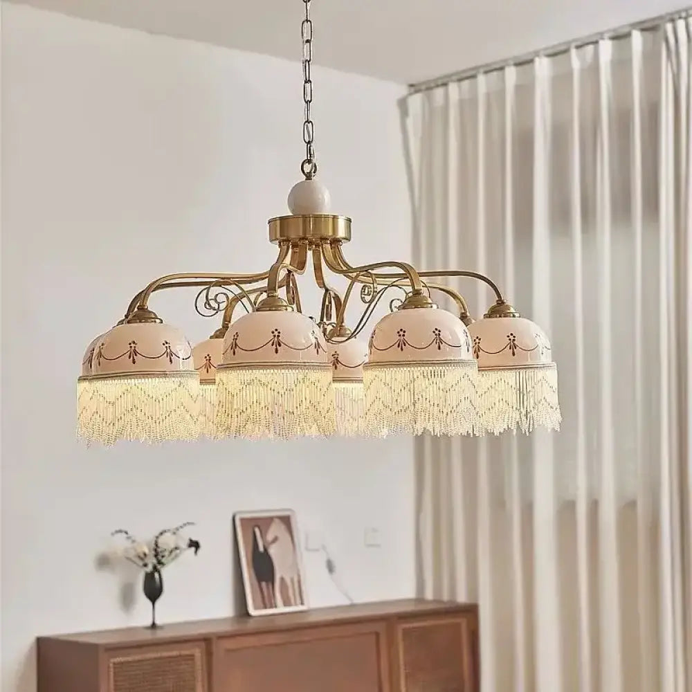 Gold multi-head pendant light with white ceramic shades, brown floral accents, tassel fringe on chain