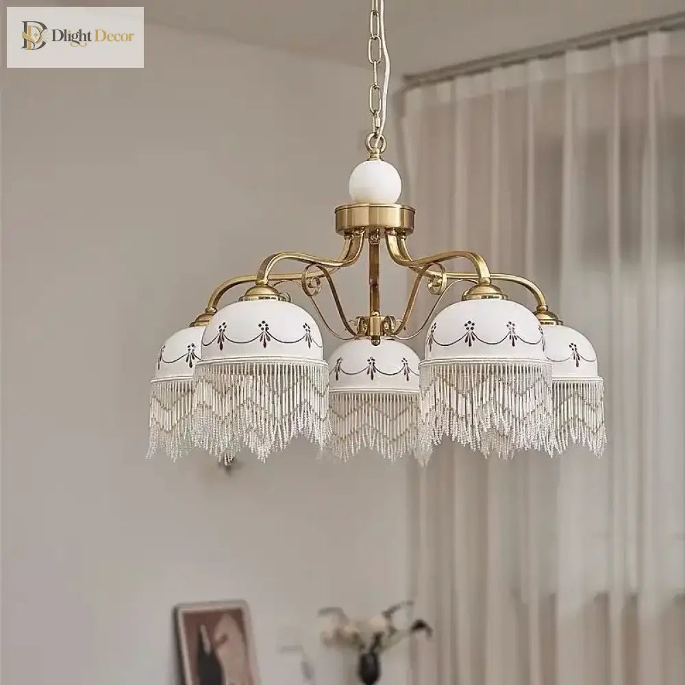 Gold multi-head pendant light with white ceramic shades and delicate tassel fringe on hanging chain