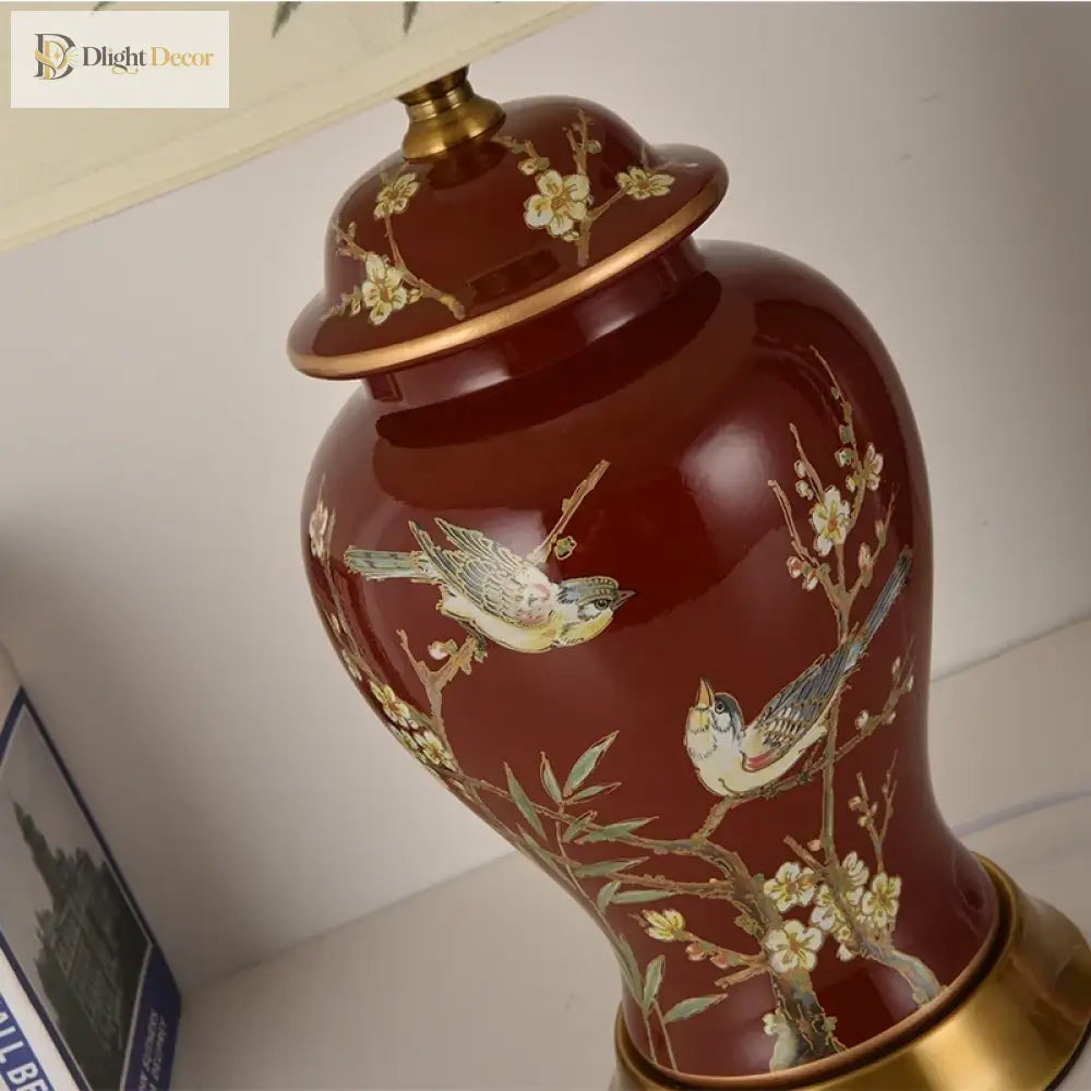 Ceramic LED desk lamp close-up: red glossy ceramic with gold bird and floral details