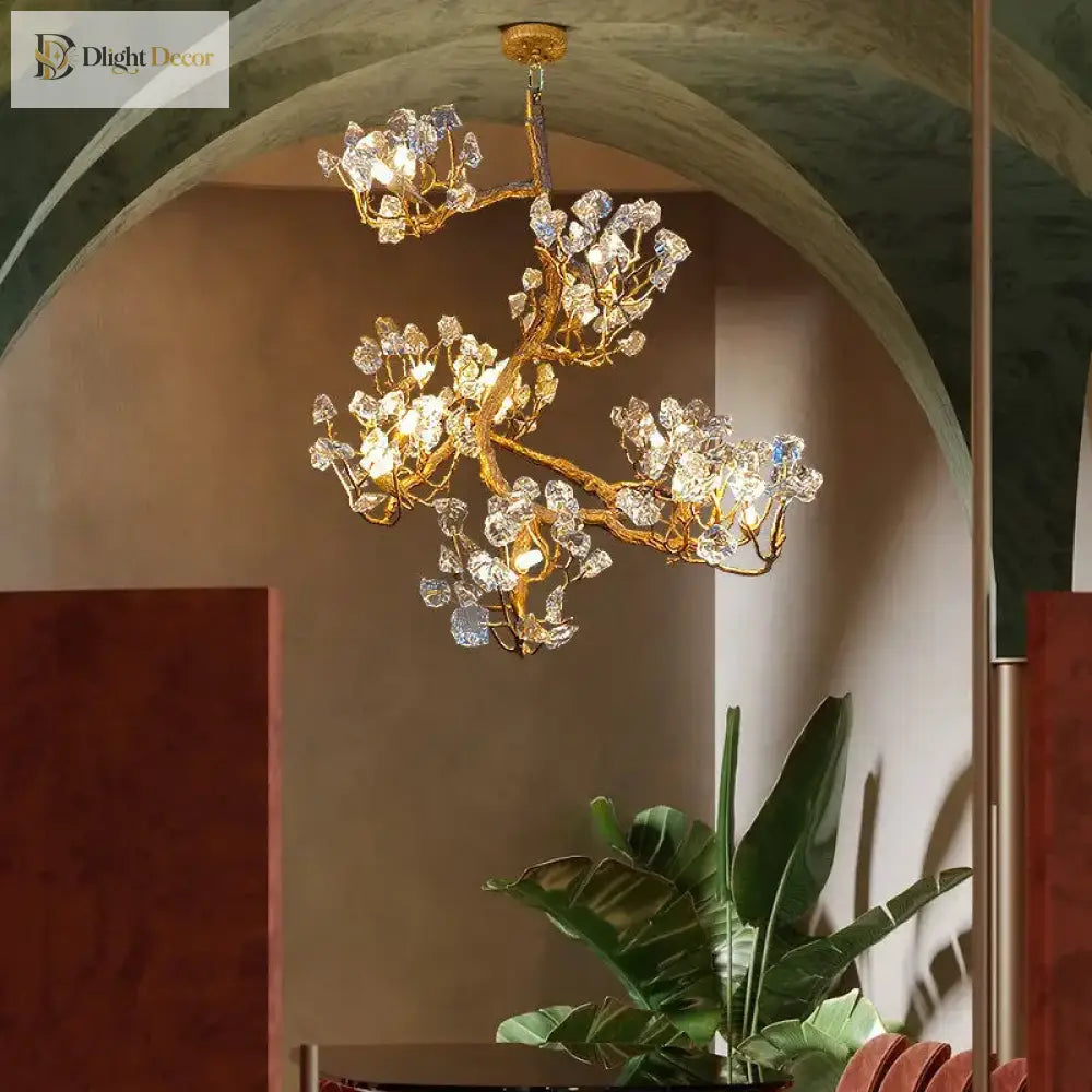 Gold-toned crystal chandelier with sculpted branching arms and sparkling clear prisms