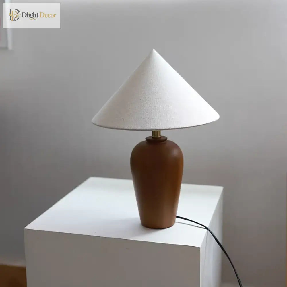 Wooden desk lamp with white cone shade and round brass-topped neck on white block