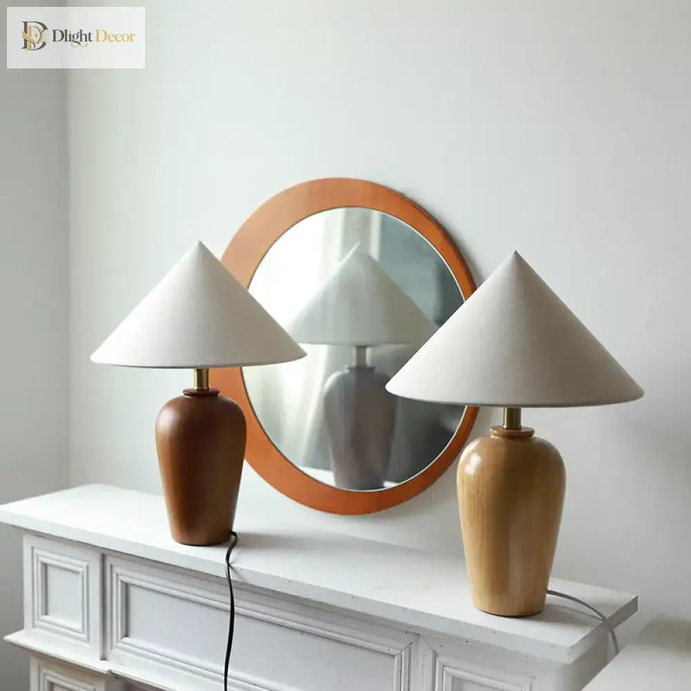 Two wooden table lamps with white cone shades and brass stems on white console