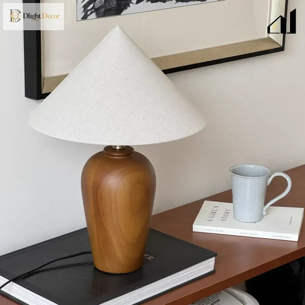 Wooden bedside lamp with white cone shade and brass finial on table