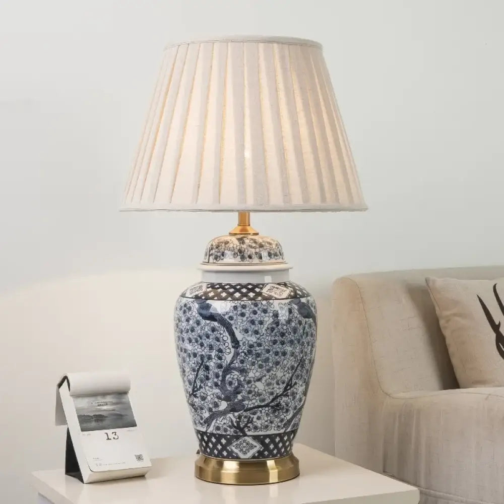 Indigo patterned ceramic lamp with beige pleated drum shade and gold base accents