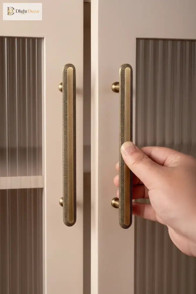 Pair of vertical cabinet bar pulls with knurled grid texture; hand pulling one.