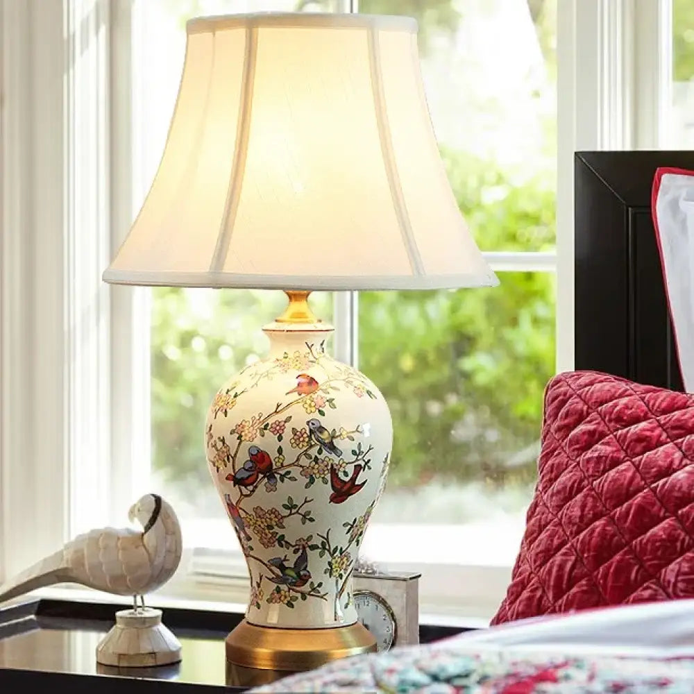 Ceramic table lamp with floral pattern, fabric shade, and brass base accents.