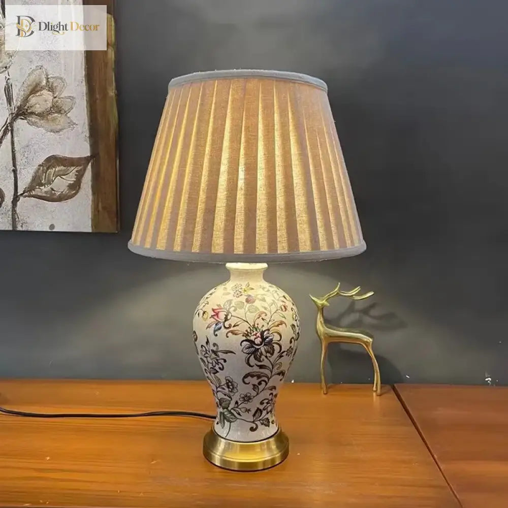 Floral ceramic table lamp with pleated beige shade and gold-bronze base
