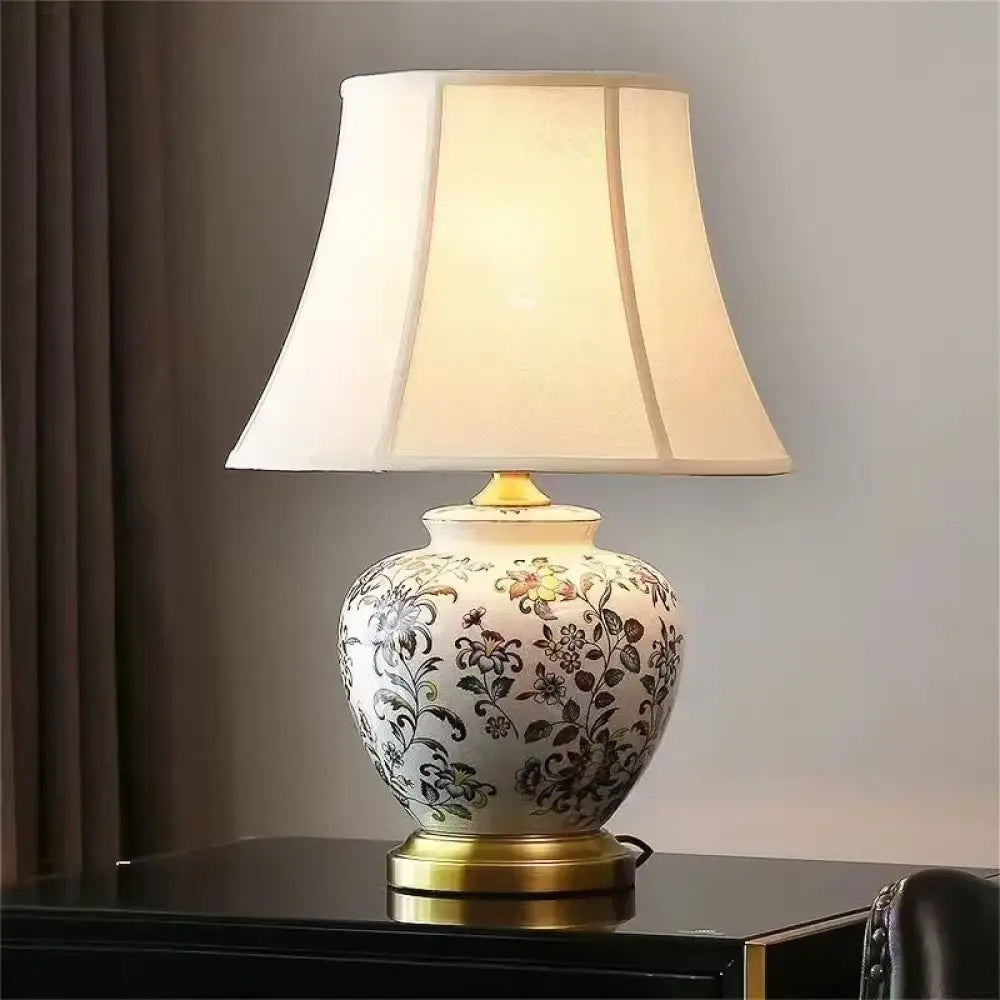 Floral ceramic table lamp with gold base, pleated shade, and brass stem