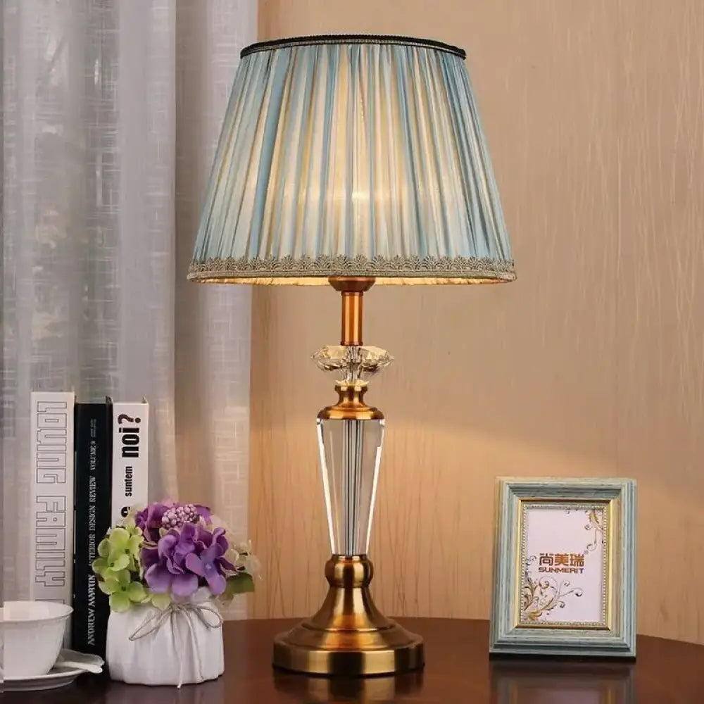 Gold and clear crystal LED table lamp with pleated teal fabric shade and finial base
