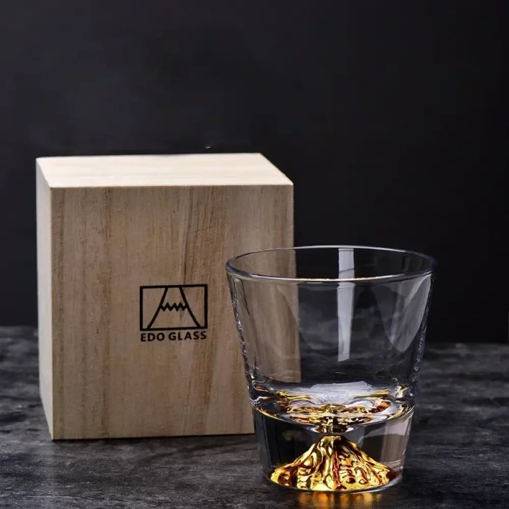 Two clear whiskey glasses with faceted bases beside a light wood storage box