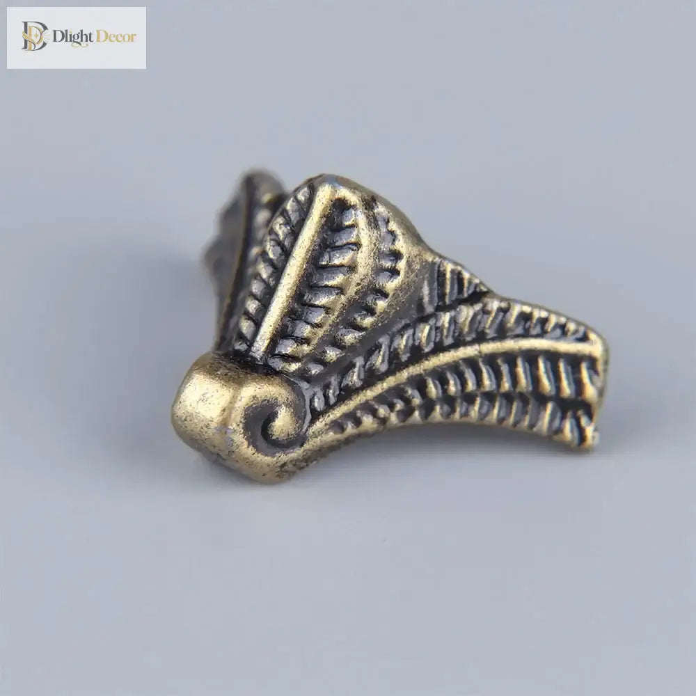 Bronze corner foot with embossed leaf-and-engraving style detailing and round base