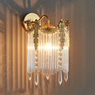Gold crystal wall sconce with arched frame and dangling crystal strands, lit