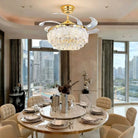 Gold ceiling fan with crystal glass light fixture and clear blades over dining table