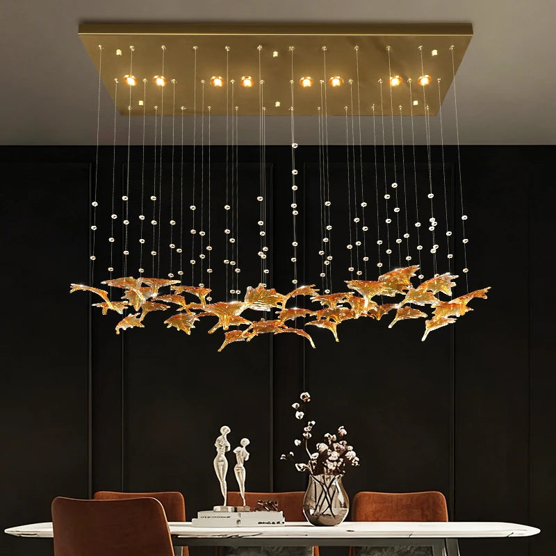 Gold glass pendant chandelier with hanging strands and warm bulbs above dining table