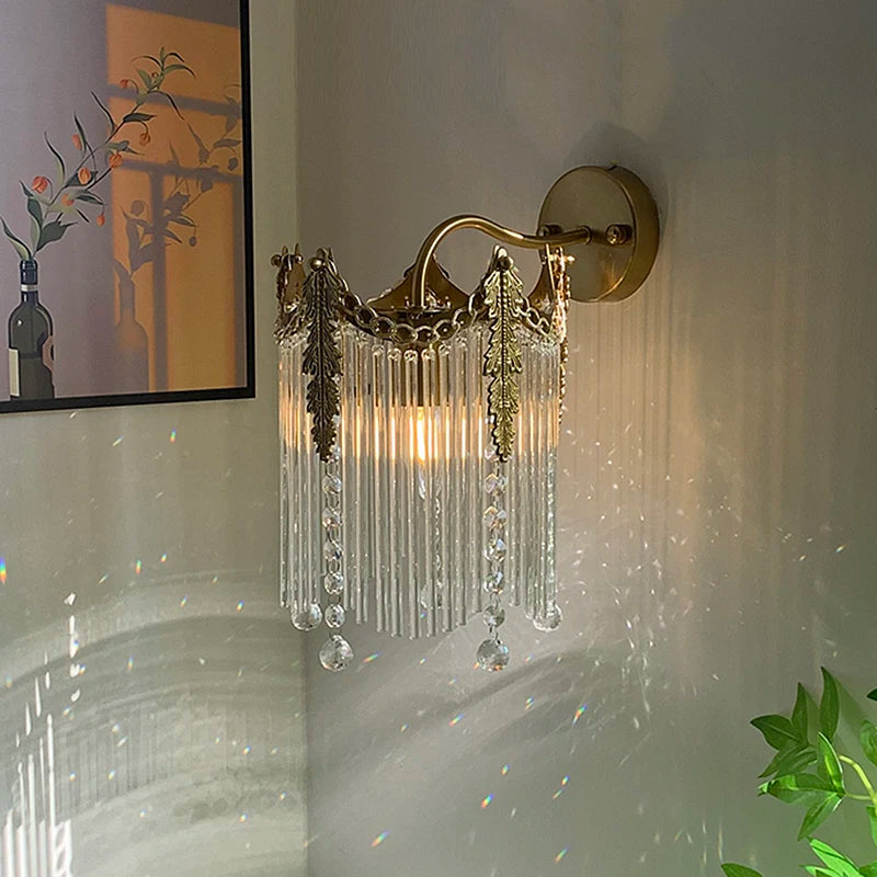 Gold crystal wall sconce with hanging crystal strands and lit bulbs behind
