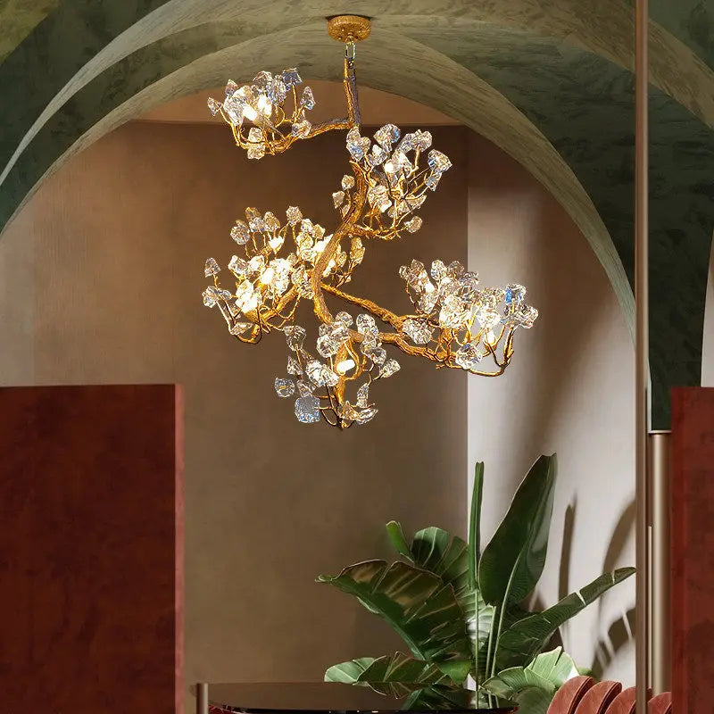 Gold-toned crystal chandelier with sculpted branching arms and sparkling clear prisms