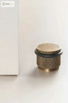 Adjustable knurled door stop with warm bronze body and black top ring, floor-mounted