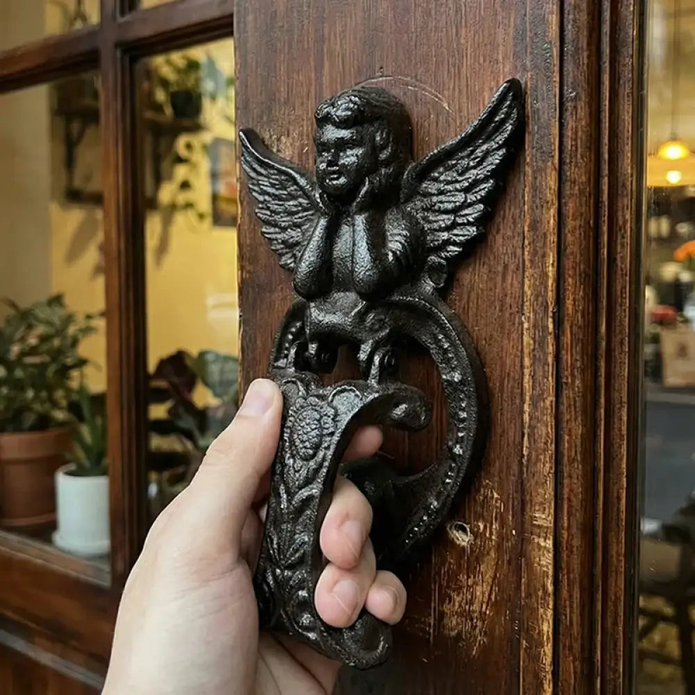 Cast iron angel door knocker with heart-shaped faceplate and wings, dark bronze finish