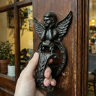 Cast iron angel door knocker with heart-shaped faceplate and wings, dark bronze finish