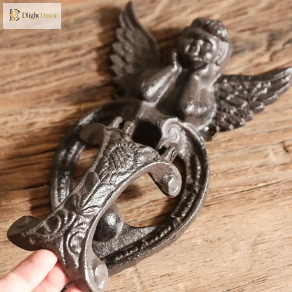 Close-up of cast iron angel door knocker showing wings, heart scroll detail, dark finish