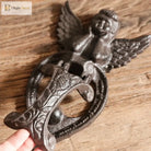 Close-up of cast iron angel door knocker showing wings, heart scroll detail, dark finish
