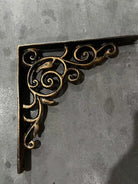Cast iron corner shelf bracket with fleur-de-lis style scrollwork, dark finish