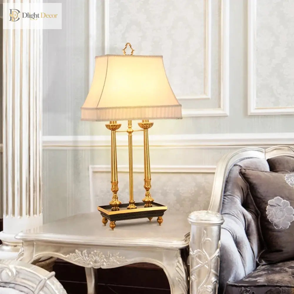 Brass LED desk lamp with beige shade on a dark base near a sofa
