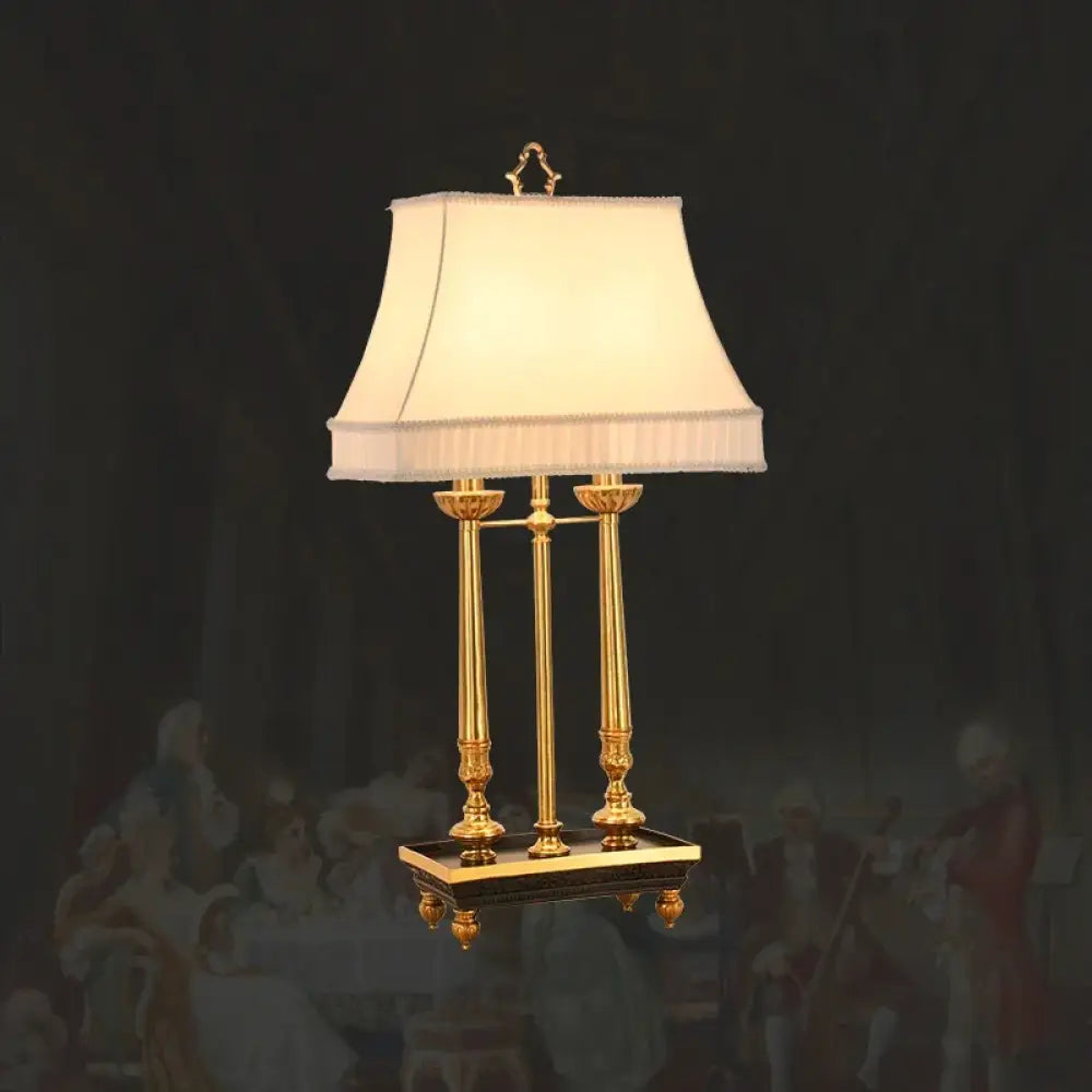 Brass LED desk lamp with beige fabric shade and three slender legs