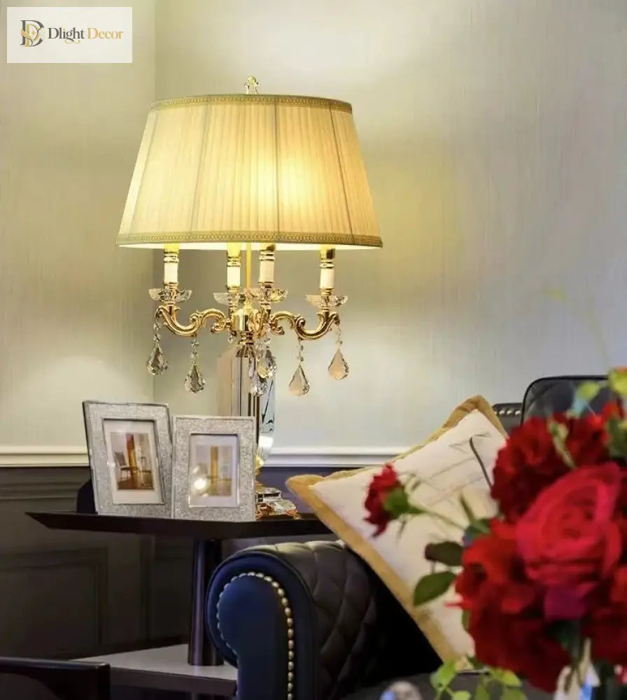 Gold LED table lamp with pleated shade and crystal drops on a decorative base