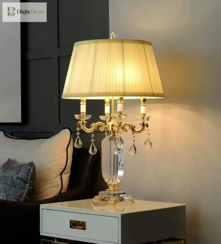 Gold LED table lamp with pleated shade, glass stem, and crystal drop accents