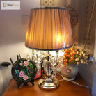 Gold crystal table lamp with amber pleated shade on bedside surface