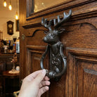 Cast iron deer head door knocker with curled handle and detailed face and antlers