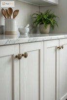 Brushed brass floral cabinet handles on white cabinet doors
