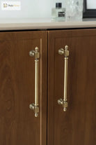 Antique brass cabinet handles on two wooden cabinet doors with finial pulls