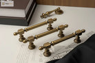 Antique brass hammered cabinet handle with knob ends and spindle-style base